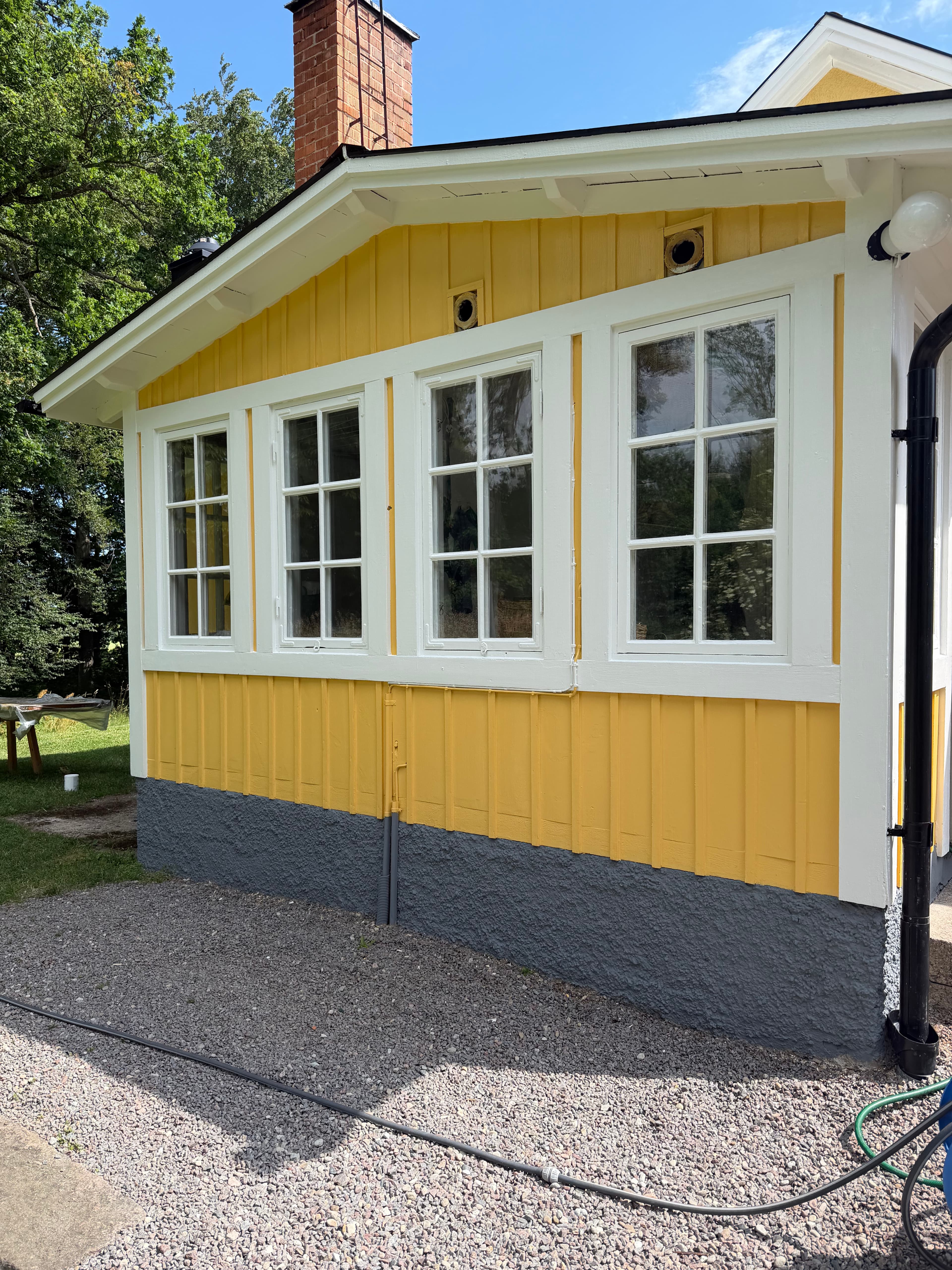 Inglasad veranda i Linköping nymålad i varm gul kulör med vita fönsterfoder